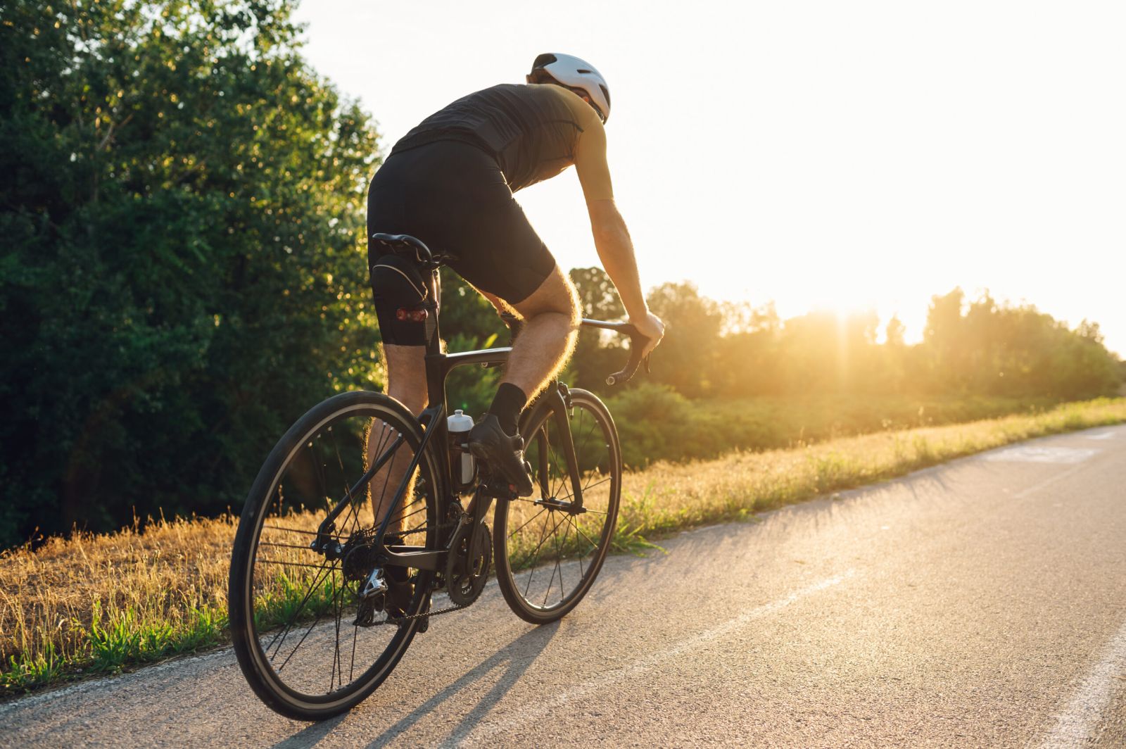 Radfahrer auf einer Landstraße im Gegenlicht