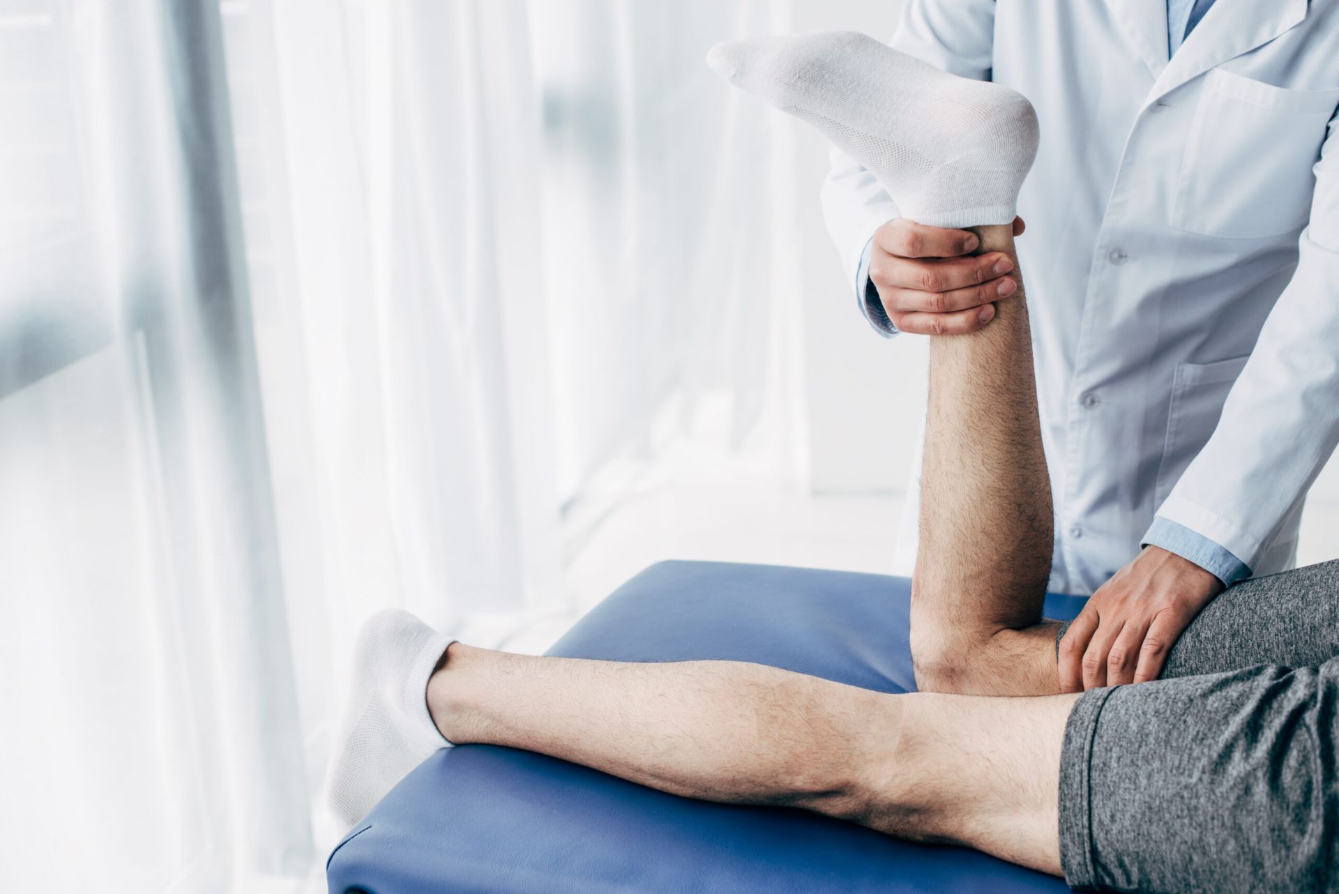 Physiotherapeut dehnt das Bein eines Patienten